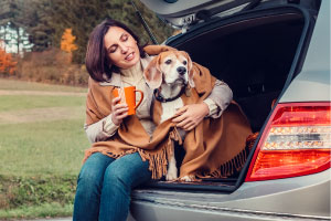 A woman and her dog bundled up in the back of a car.